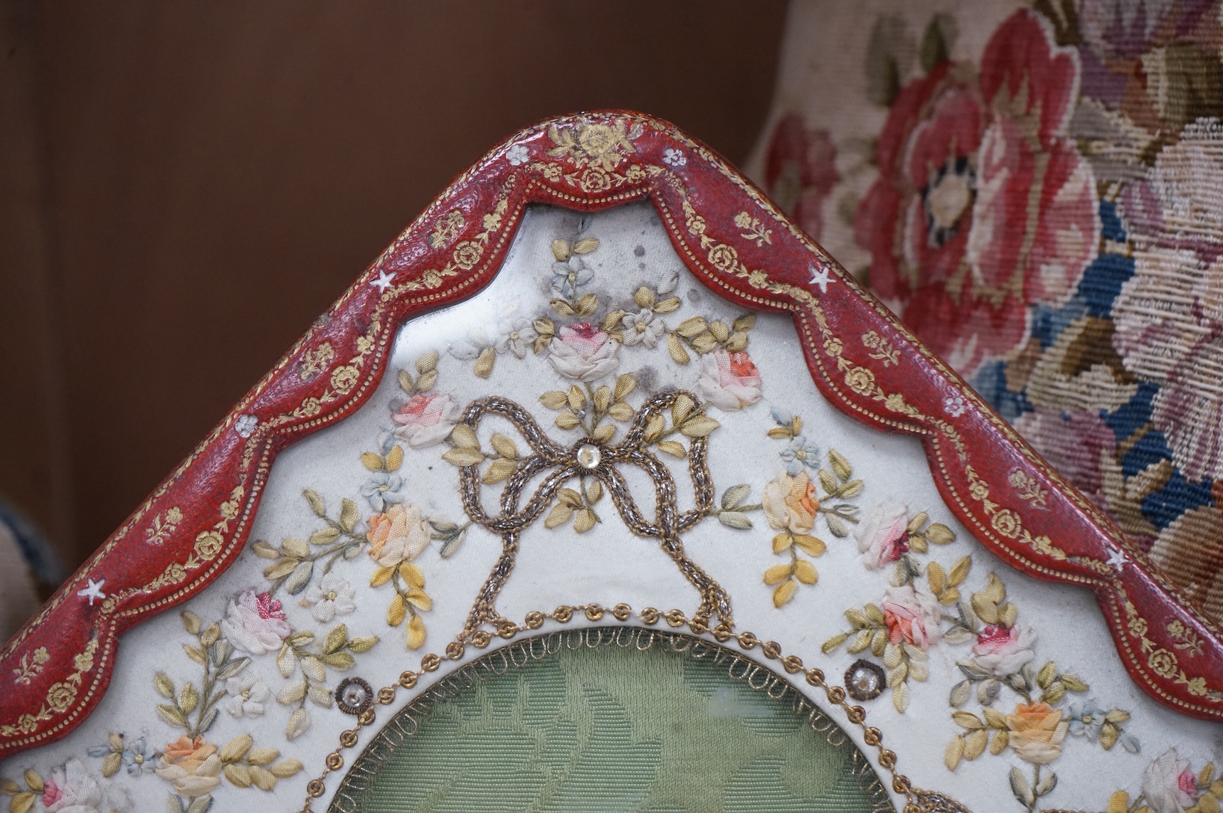 An Edwardian decorative stamped gilt leather photo frame, with bow to base and a floral patterned ribbon and sequin work front panel. 27.5cm high. Condition -good